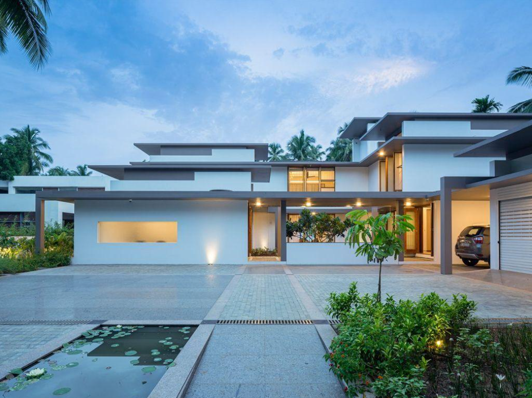 Low horizontal white home with layered flat roofs and a lily pond in the forecourt