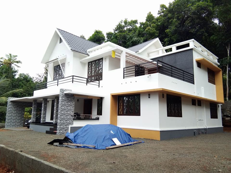 Side elevation of a completed white home with balconies and dark tiled roofs