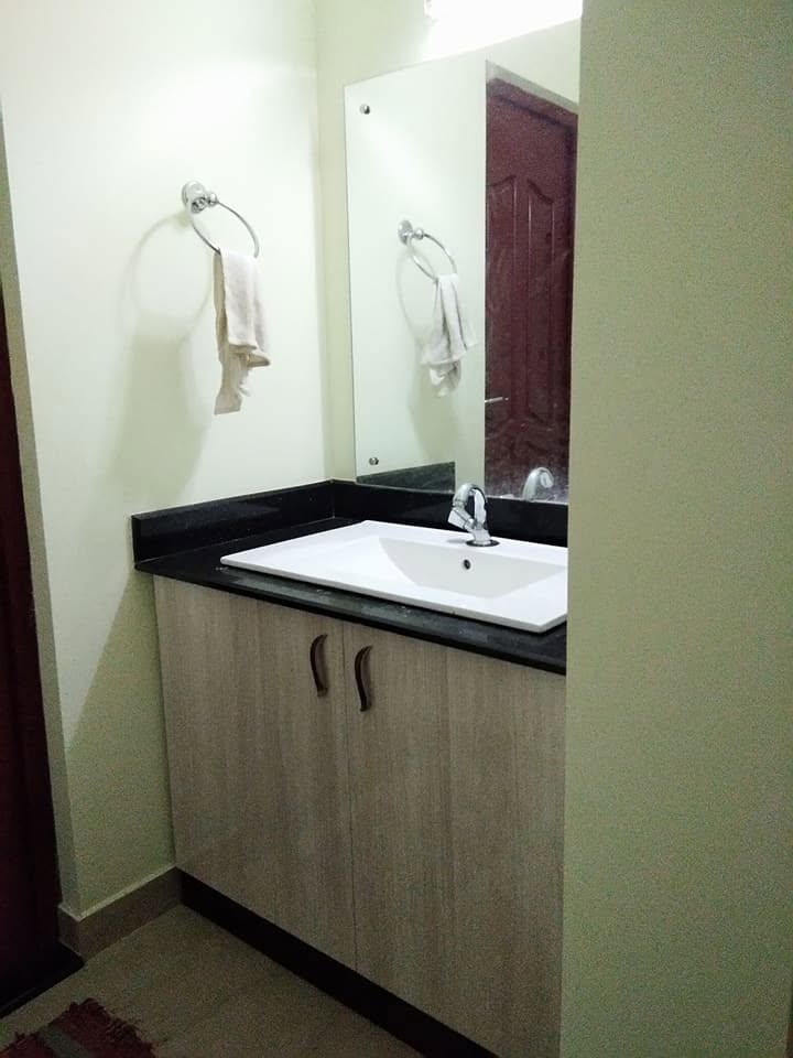 Completed wash area with floating vanity, mirror and black stone counter