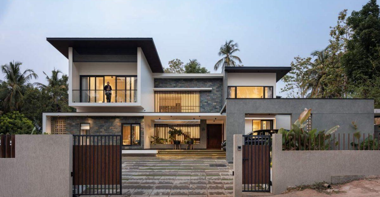 Contemporary home with stone-clad walls, timber louvres and a wide paved driveway at dusk