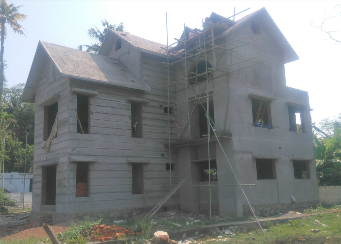 Side view of the plastered home structure with roof work in progress